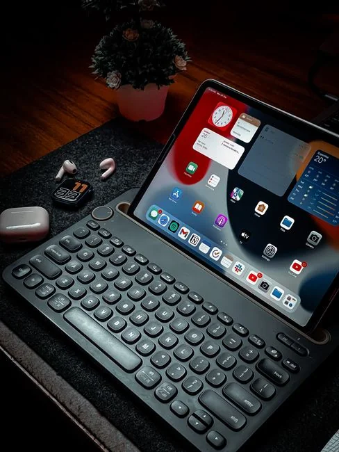 Business professional using a tablet and laptop with a hot drink, focusing on digital content review.